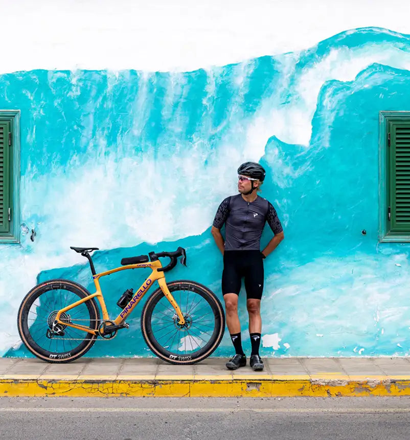 Person with a bicycle leaning against a blue wall with wave design